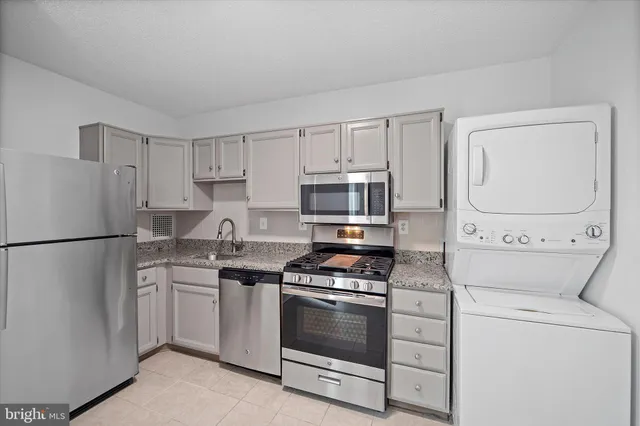 a kitchen with granite countertop white cabinets and stainless steel appliances