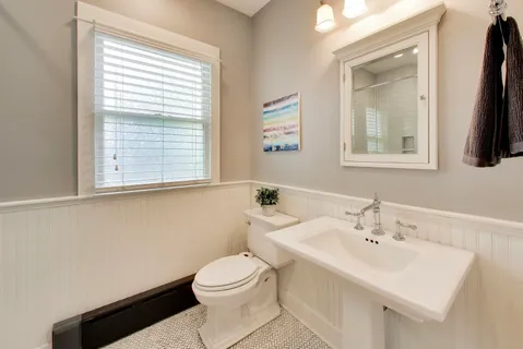 a bathroom with a toilet a sink a mirror and a window