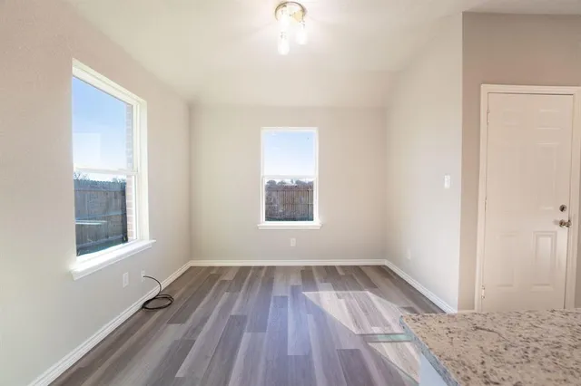 a view of an empty room and window and wooden floor