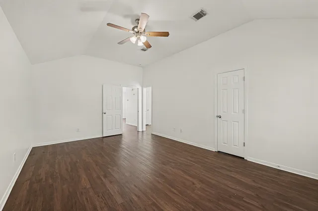 an empty room with wooden floor and ceiling fan