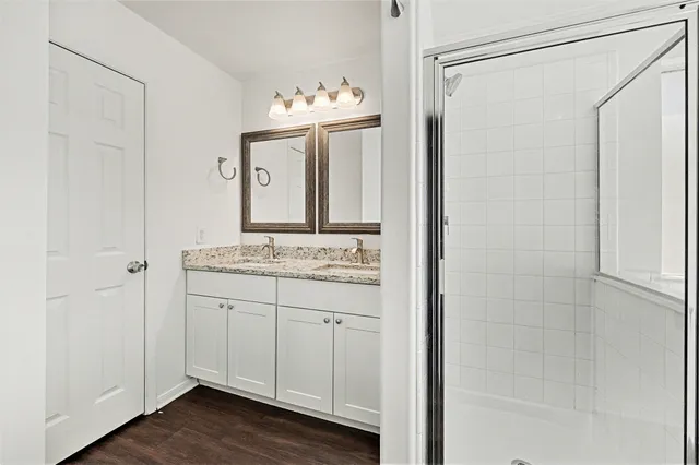 a bathroom with a granite countertop sink a mirror and shower