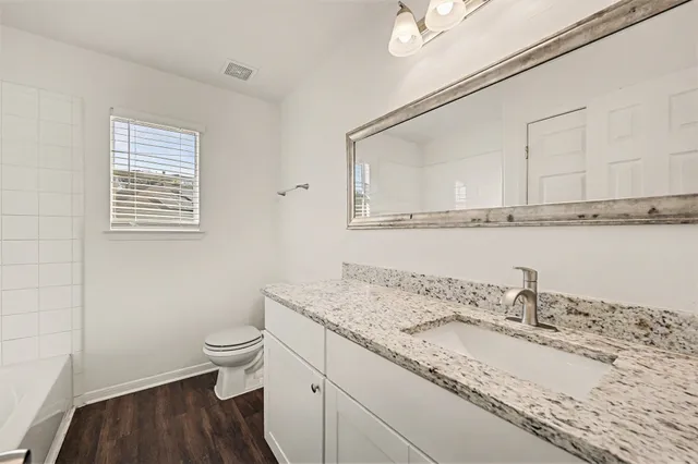 a bathroom with a granite countertop sink a toilet and a mirror