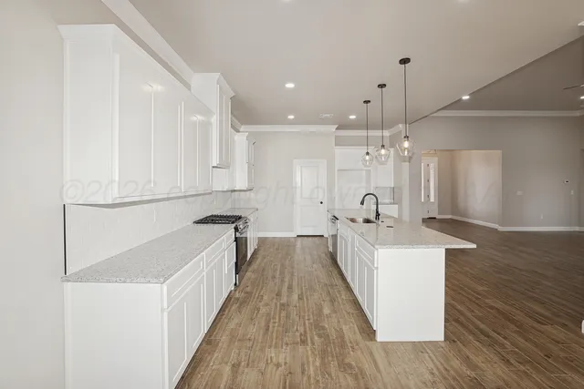 a view of a kitchen with kitchen island a sink wooden floor and stainless steel appliances