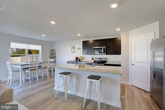 a kitchen with stainless steel appliances granite countertop a table chairs sink and cabinets