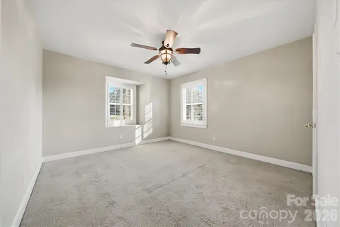 an empty room with windows and fireplace