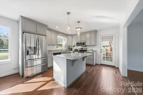 a kitchen with stainless steel appliances granite countertop a sink dishwasher a stove and a refrigerator with wooden floor