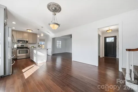an empty room with wooden floor staircase and windows