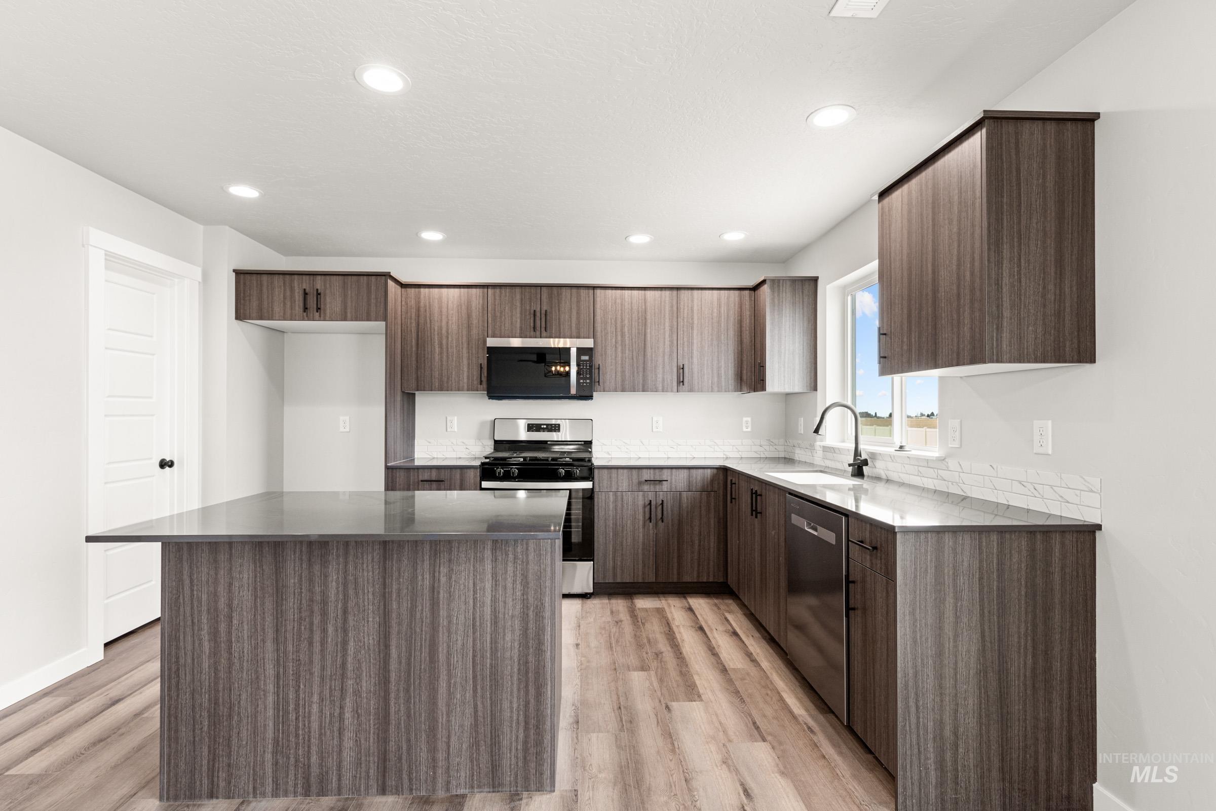 12830 Ropers Street Nampa, ID 83651 - Photo 4 of 18 Kitchen featuring a central island, wood-finish flooring, dark wood-finish cabinetry, stainless steel appliances, and recessed lighting