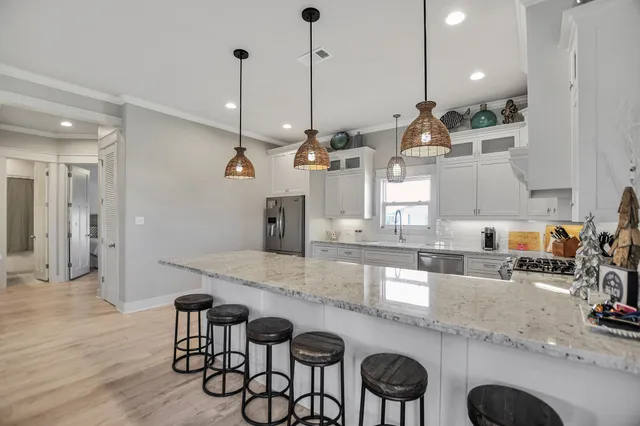 a kitchen with granite countertop a sink a stove and chairs