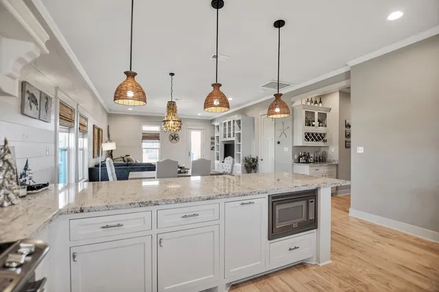 a kitchen with stainless steel appliances granite countertop a sink a window and white cabinets