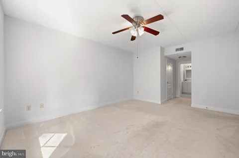 an empty room with closet and a ceiling fan