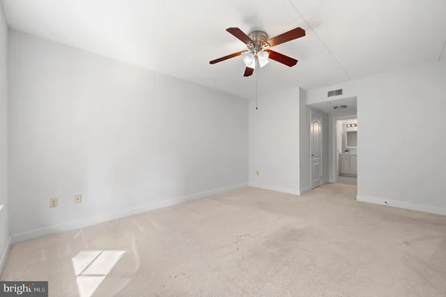 an empty room with closet and a ceiling fan