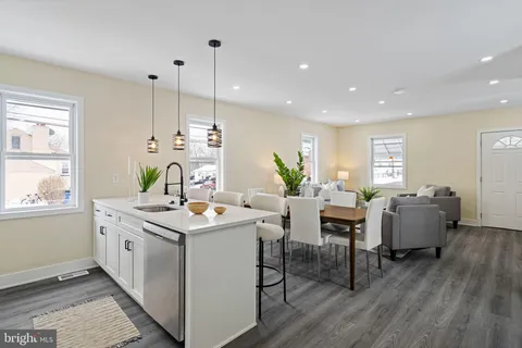 a room with stainless steel appliances kitchen island granite countertop a table chairs and a wooden floor