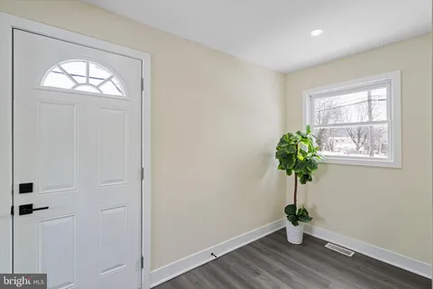 a view of empty room with wooden floor and window