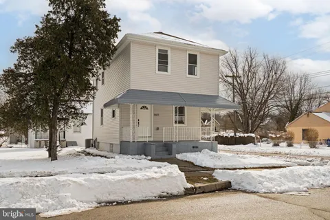 a front view of a house with a yard covered with snow