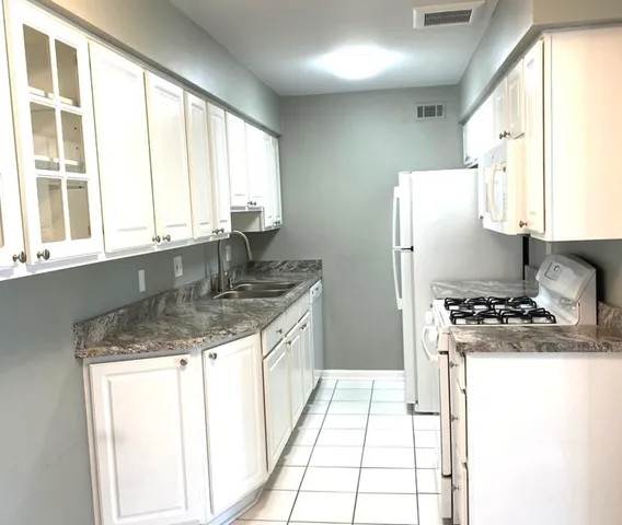 a kitchen with granite countertop a sink stove and refrigerator