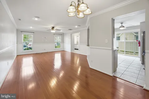 a view of an empty room with wooden floor and a kitchen