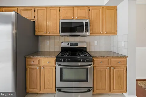 a kitchen with stainless steel appliances granite countertop white cabinets and a stove top oven
