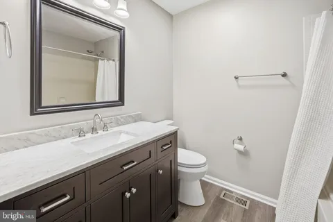 a bathroom with a granite countertop sink toilet and mirror