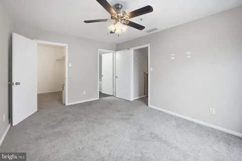 an empty room with closet and a ceiling fan