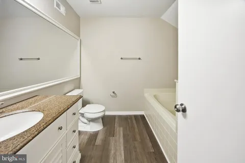 a bathroom with a granite countertop toilet a sink and a mirror