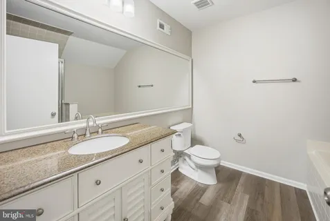 a bathroom with a granite countertop sink a toilet and a mirror