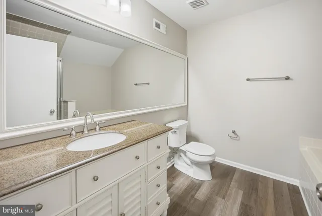 a bathroom with a granite countertop sink a toilet and a mirror