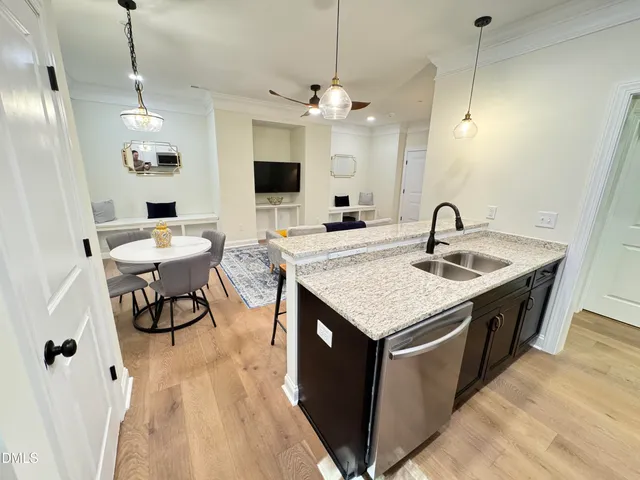 a kitchen with a stove center island a dining table and chairs with wooden floor