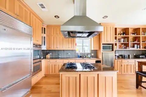 a kitchen with stainless steel appliances a stove a refrigerator a sink a dining table and chairs