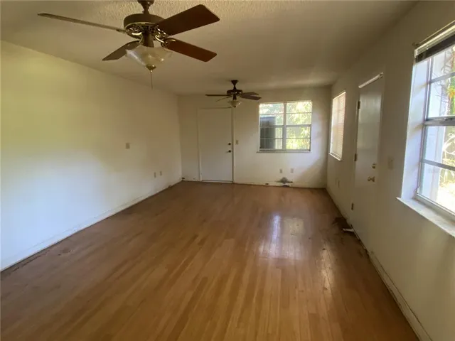 a view of empty room with wooden floor and fan