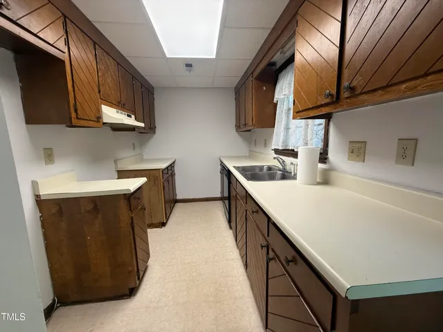 a kitchen with stainless steel appliances a sink a stove top oven a counter space and cabinets