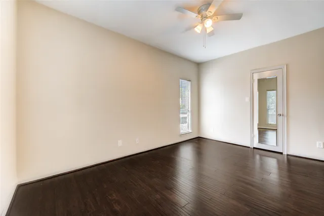 a view of an empty room with window and wooden floor
