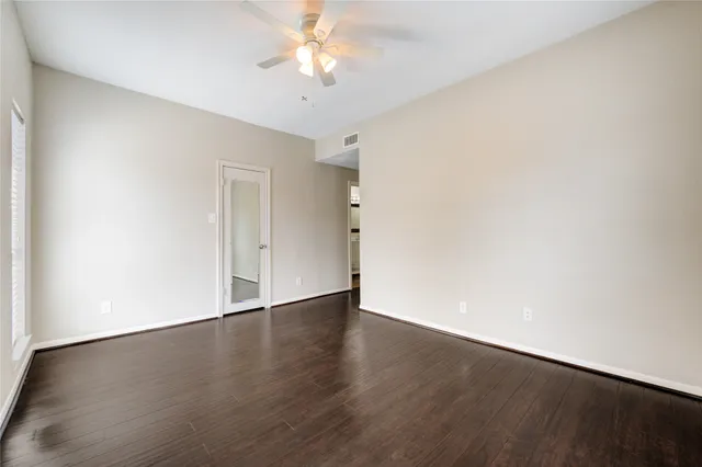 an empty room with wooden floor and ceiling fan