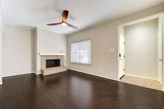 an empty room with wooden floor fireplace and windows