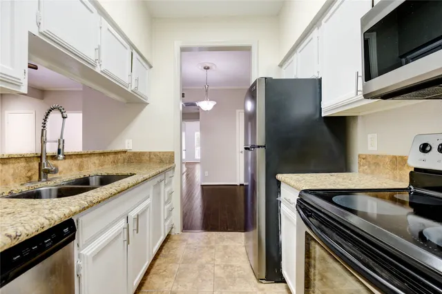 a kitchen with stainless steel appliances granite countertop a sink and a refrigerator