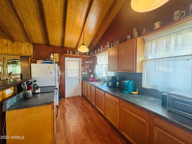 a kitchen with stainless steel appliances granite countertop a refrigerator a sink dishwasher and white cabinets with wooden floor