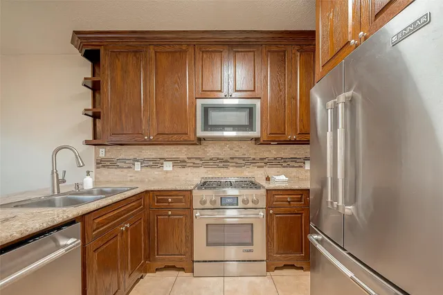 a kitchen with stainless steel appliances granite countertop a stove a sink and a microwave