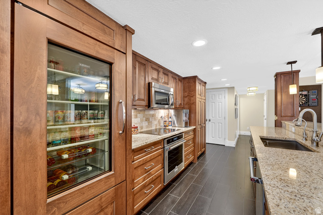 714 Draper Heights Way Draper, UT 84020 - Photo 55 of 88 Kitchen featuring light stone countertops, pendant lighting, stainless steel appliances, wood finish cabinetry, and tasteful backsplash