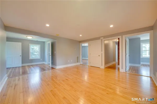 a view of an empty room with window and wooden floor