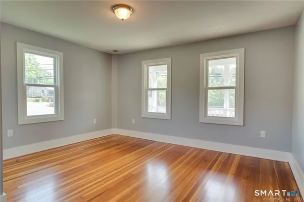 a view of an empty room with wooden floor and a window