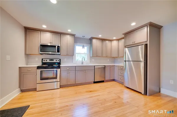 a kitchen with a refrigerator a stove top oven and wooden floor