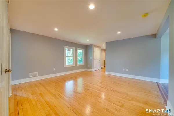 a view of an empty room with window and wooden floor