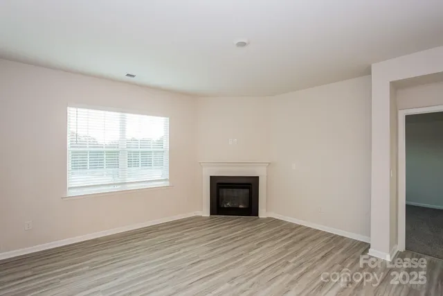 an empty room with wooden floor cabinet and windows