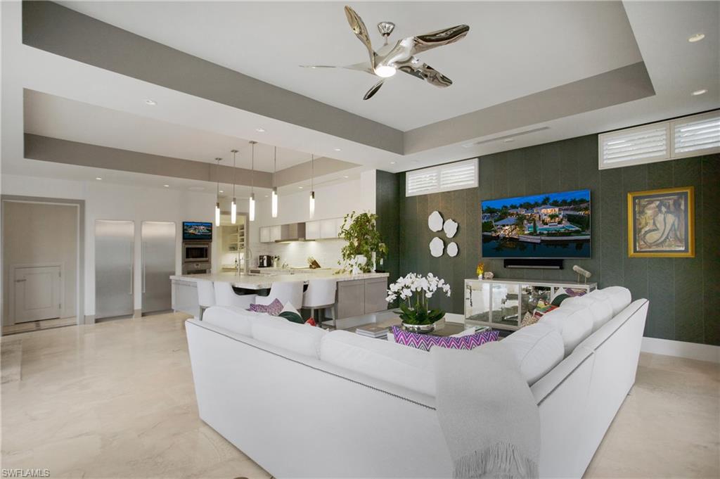 2290 Tarpon Road Naples, FL 34102 - Photo 29 of 50 Open-concept living space featuring a curved white sectional sofa, polished concrete flooring, and a coffered ceiling with integrated recessed lighting and ceiling fan