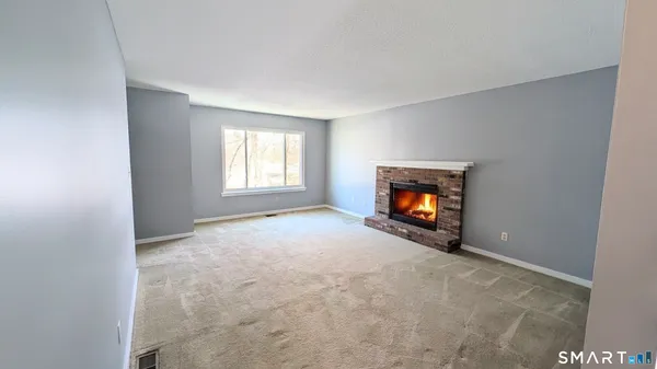 a view of an empty room with window and fire place