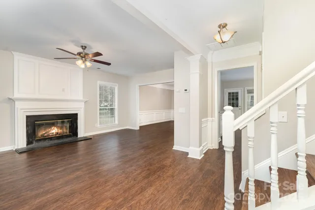a view of an empty room with wooden floor fireplace and a window
