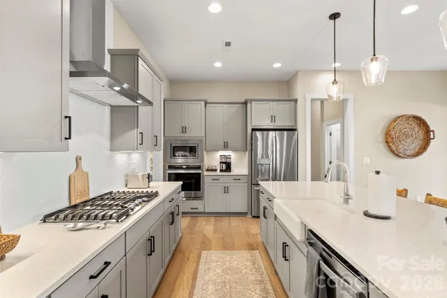 a large kitchen with stainless steel appliances a stove a sink dishwasher and a refrigerator with wooden floor