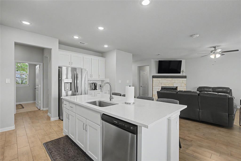 185 Chester Road Springtown, TX 76082 - Photo 18 of 40 Open-concept kitchen featuring white cabinetry, stainless steel appliances, a center island with sink, and light-toned countertops