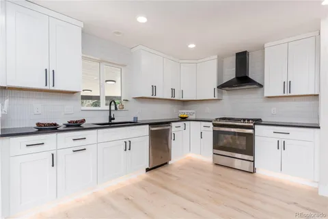 a kitchen with granite countertop white cabinets and appliances