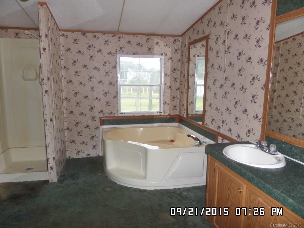 8480 Smith Road Kannapolis, NC 28081 - Photo 9 of 11 a bathroom with a granite countertop sink a mirror and a bathtub
